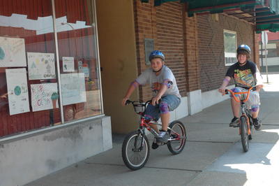 Adam Arnold, 14, of Fort Scott, demonstrates the proper use of bicycle safety equipment including the use of a helmet, elbow pads and knee pads while riding his bike Wednesday afternoon in downtown Fort Scott. Rayma Silvers/ Tribune Photo