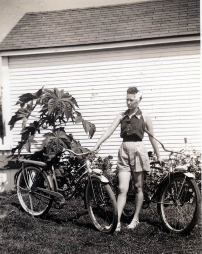 Mary Welch Steinhoff holds bikes in front of garage in Advance M