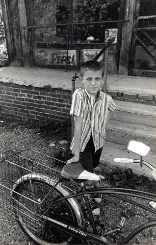 Boy with bike in front of general store in Hemlock, OH, circa 1968